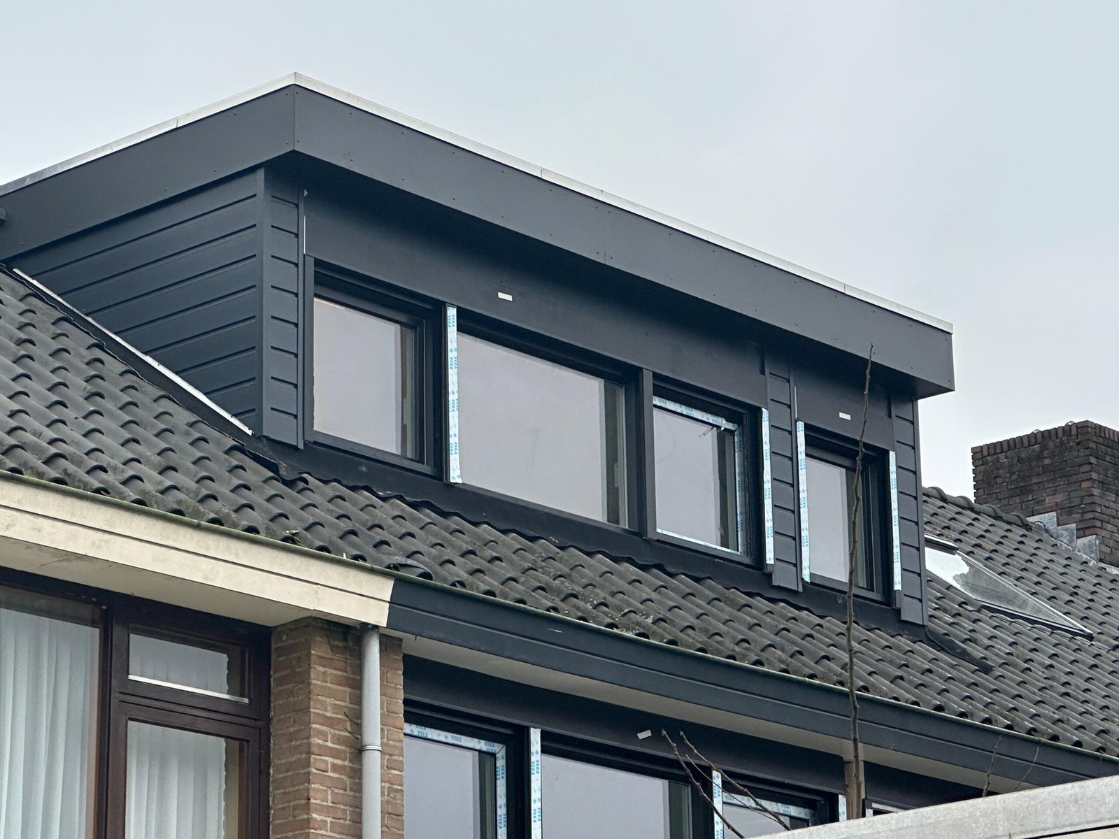 Antraciet dakkapel met ingebouwde rolluiken op een woning