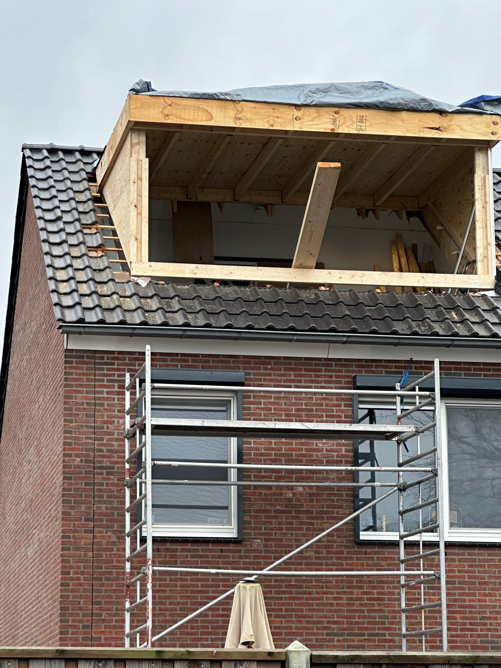 Houten constructie van een dakkapel tijdens de plaatsing, gezien vanaf de steiger